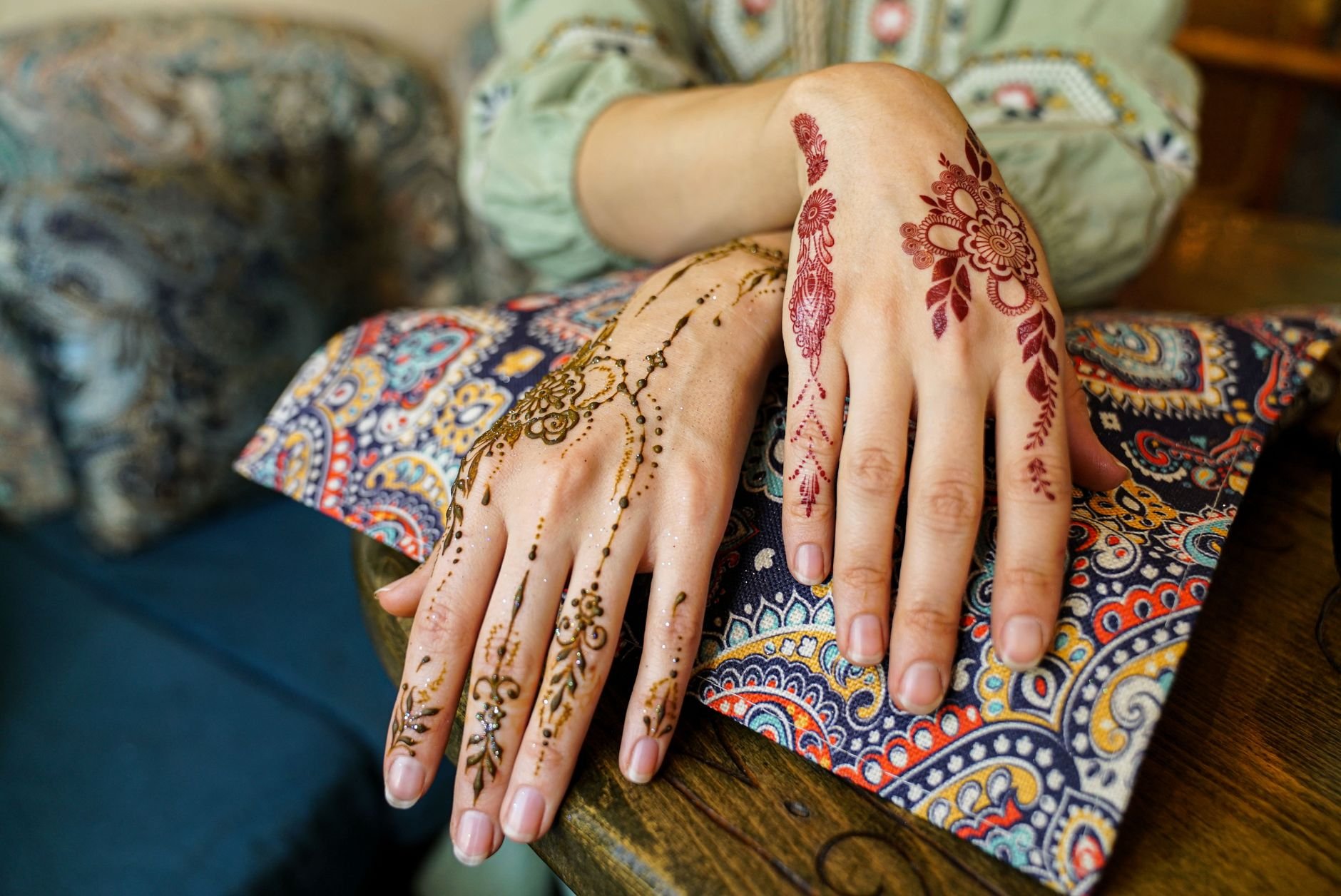 Close-up of intricate henna designs on hands, complemented by colorful textile patterns.