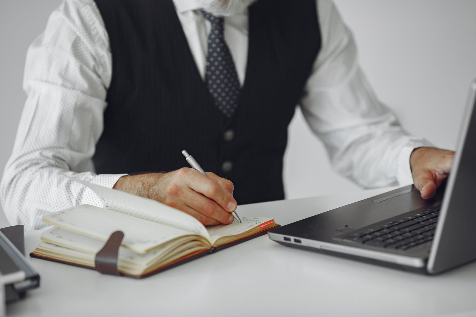 Business professional writing notes while working at a desk.