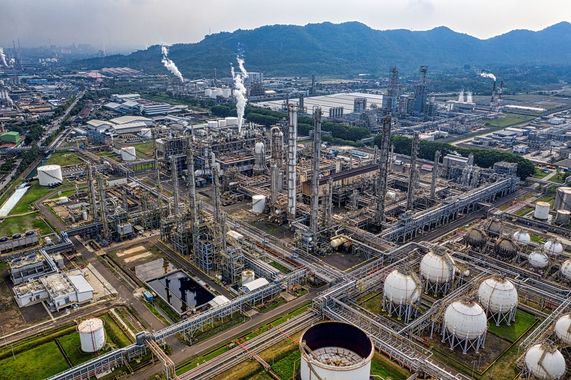 Aerial view of a large industrial oil refinery with storage tanks and pipelines.