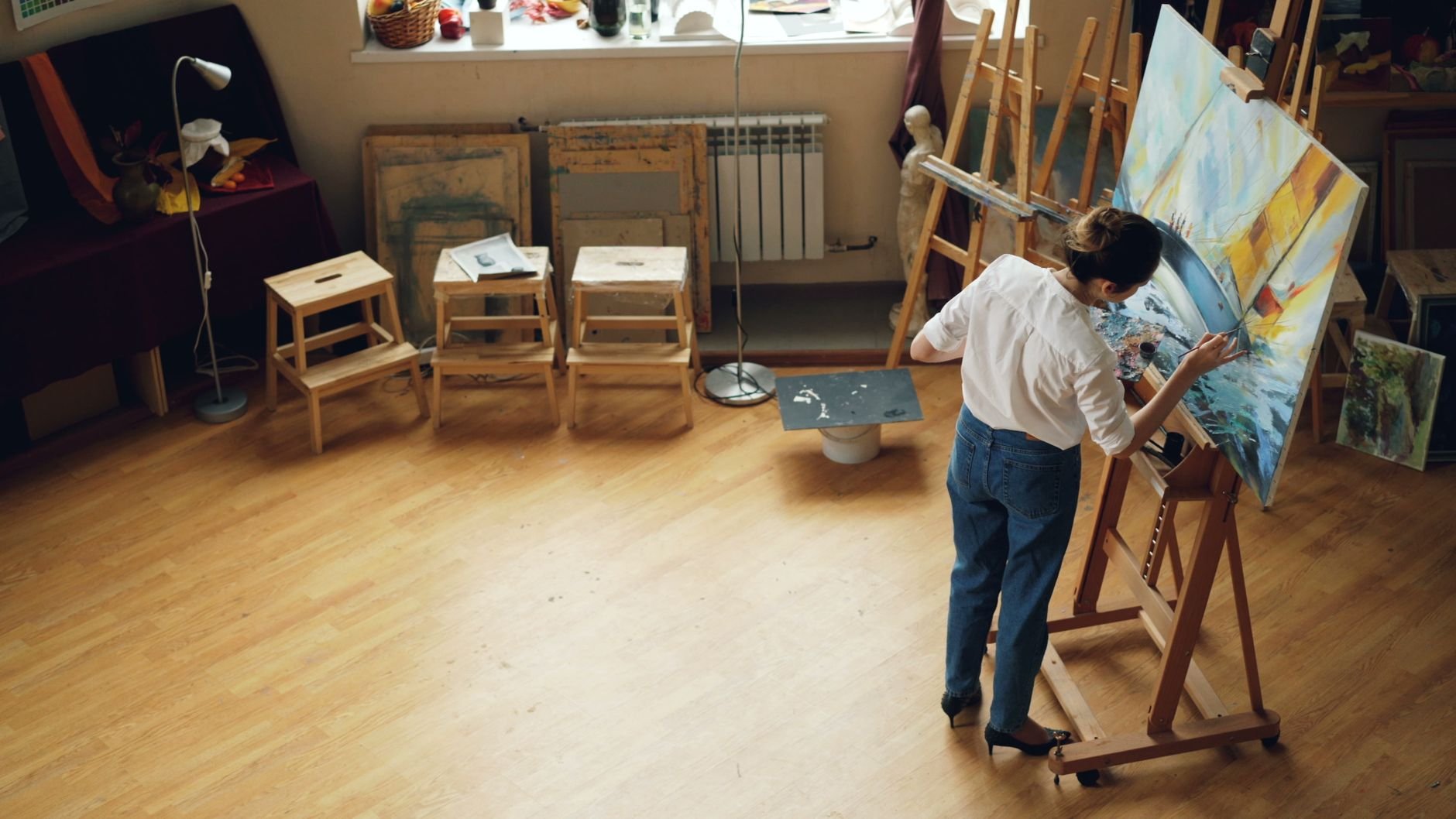 A woman painting on canvas in an artist's studio