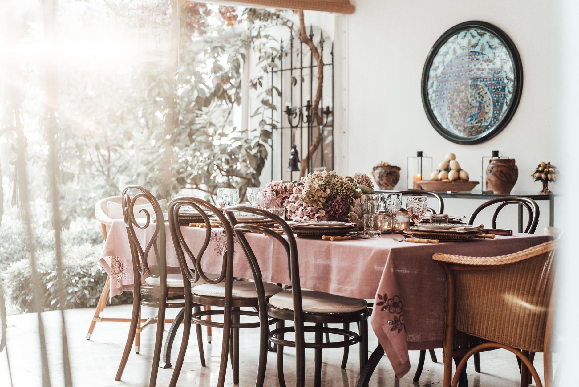 Interior of dining room with table served with dishware and glassware placed near decorative flowers for festive event