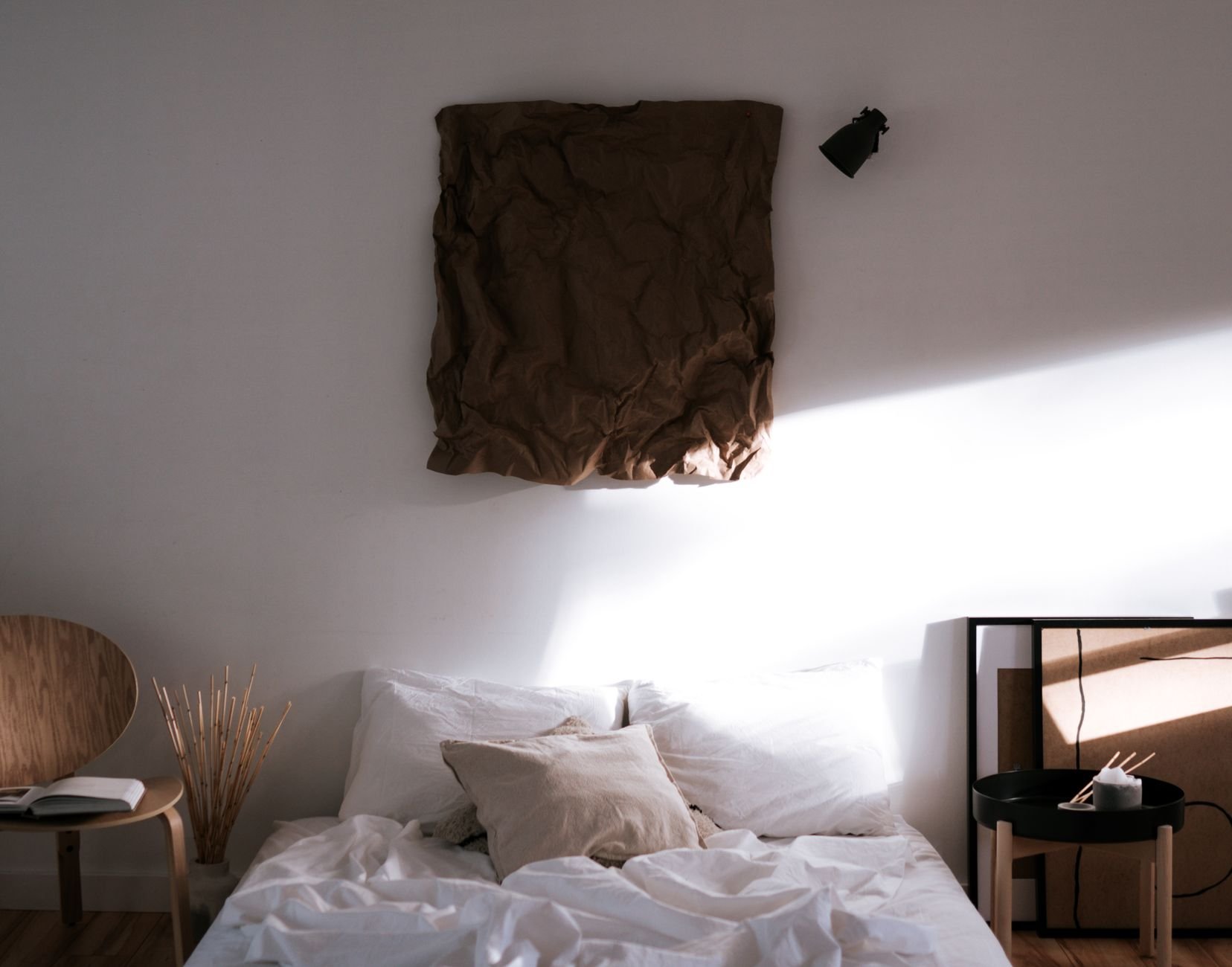 Stylish minimalist bedroom with sunlight, neutral tones, and natural materials for a serene ambiance.