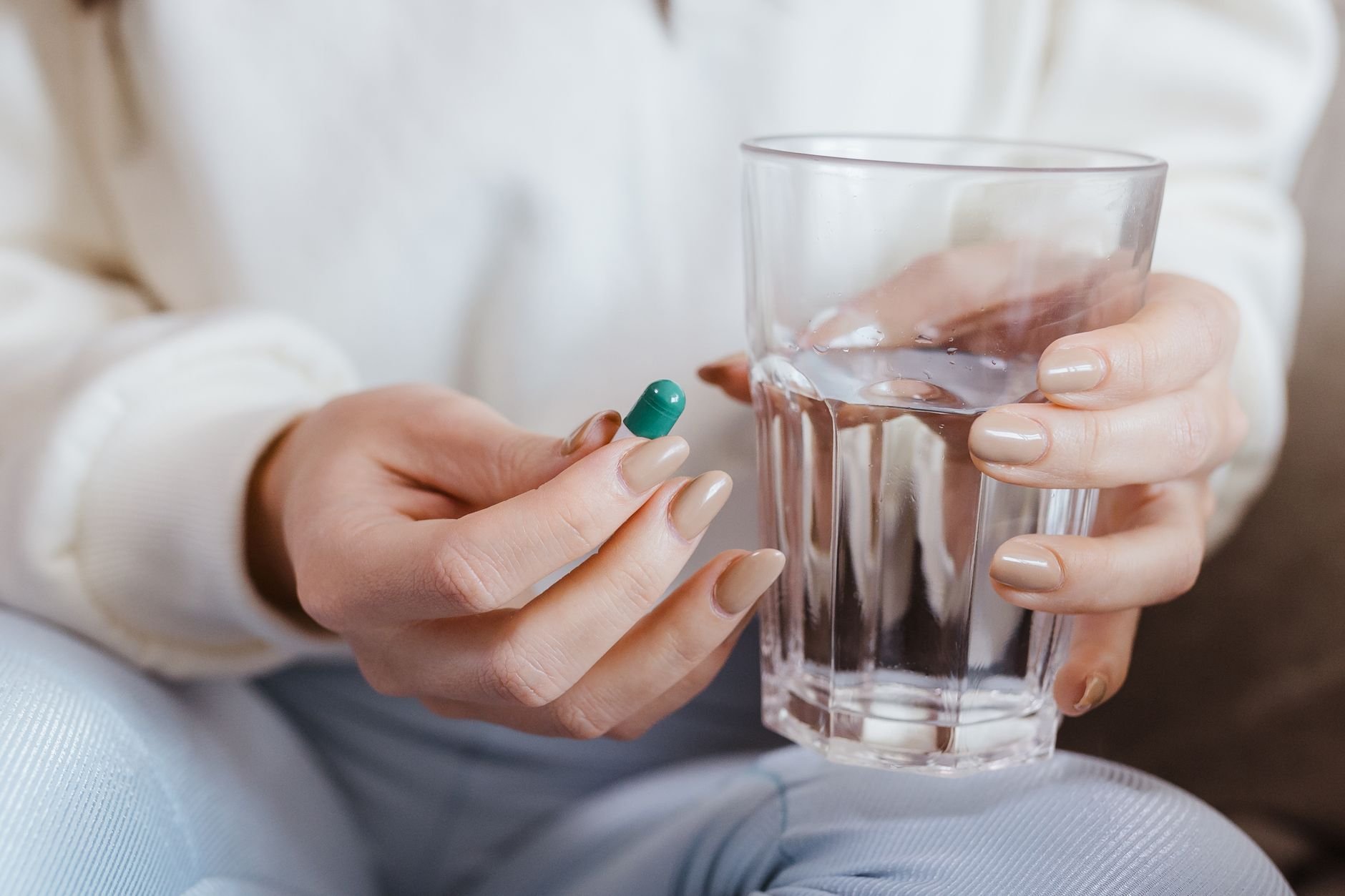 Woman taking GLP-1 medication with a glass of water — staying consistent with treatment