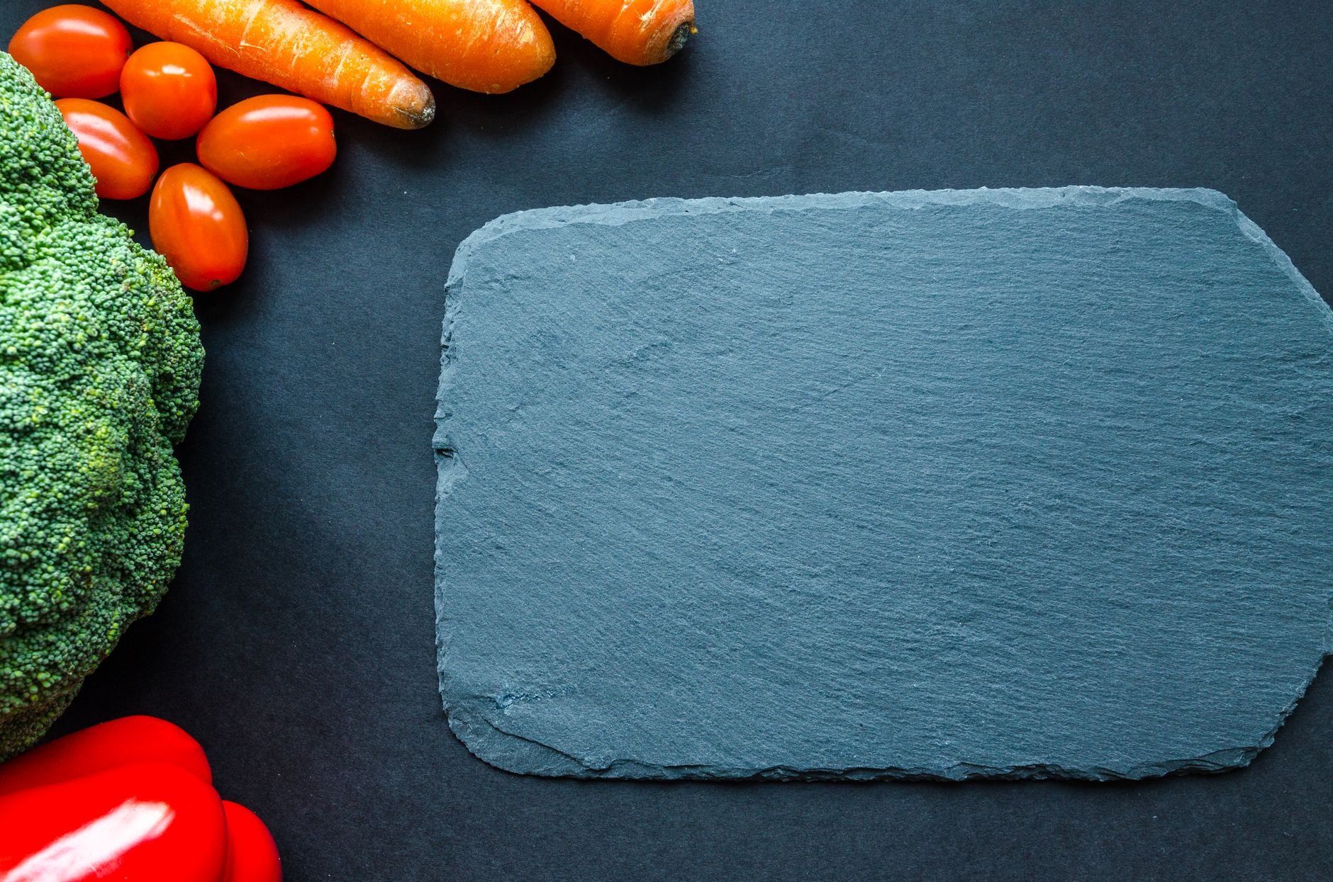 Colorful vegetables on a slate board, perfect for healthy cooking themes.