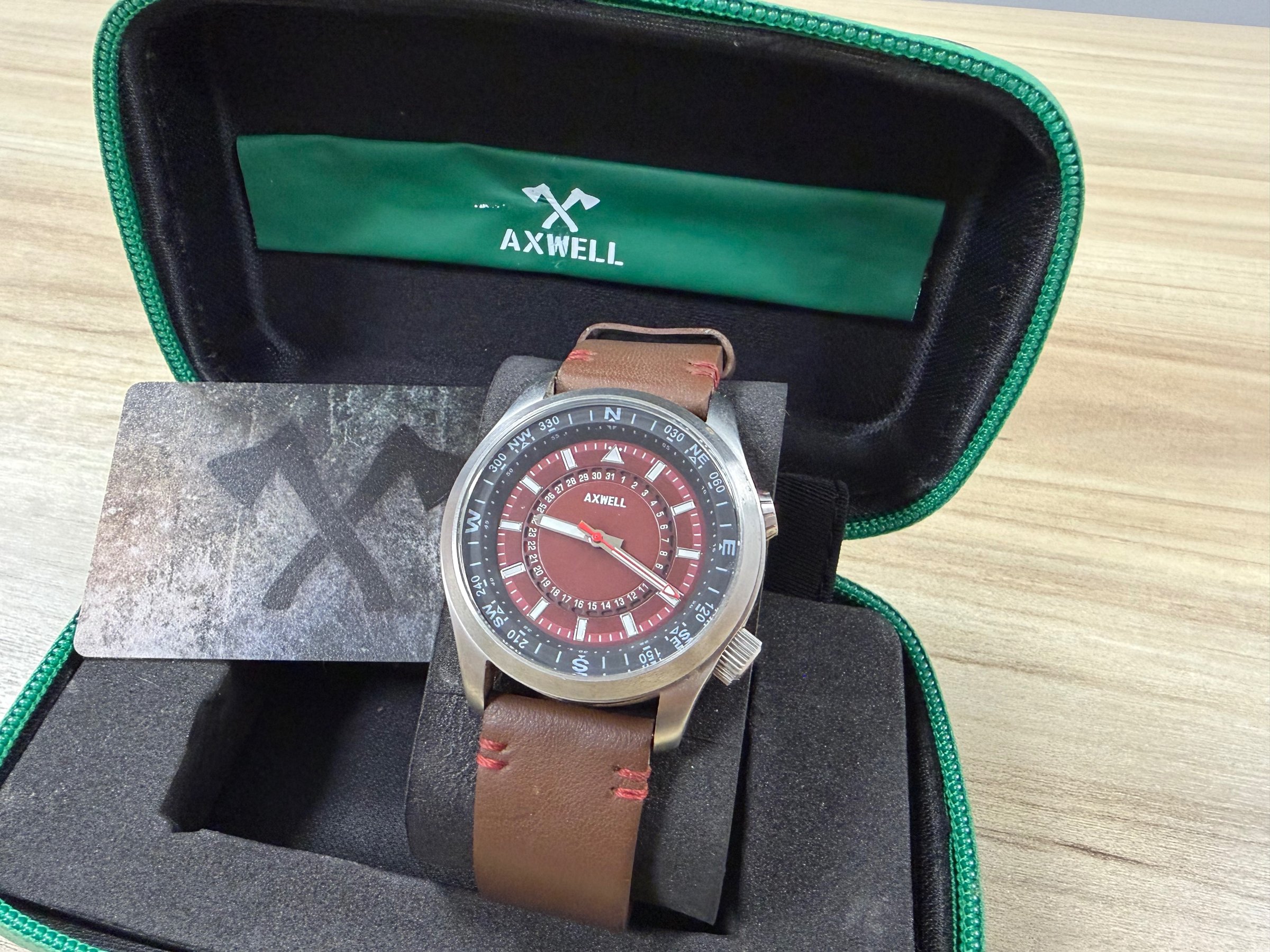 Axwell World Compass Adventurer automatic watch with red dial and compass bezel in green zipper case
