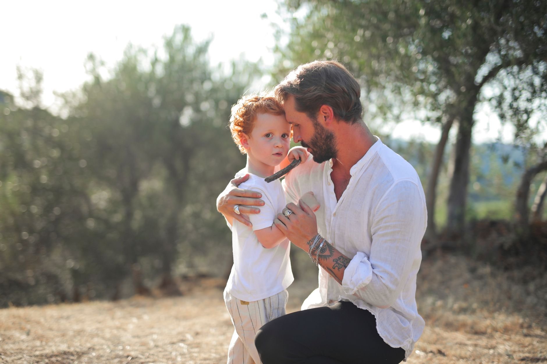 Heartwarming outdoor scene of a father embracing his young son among trees.
