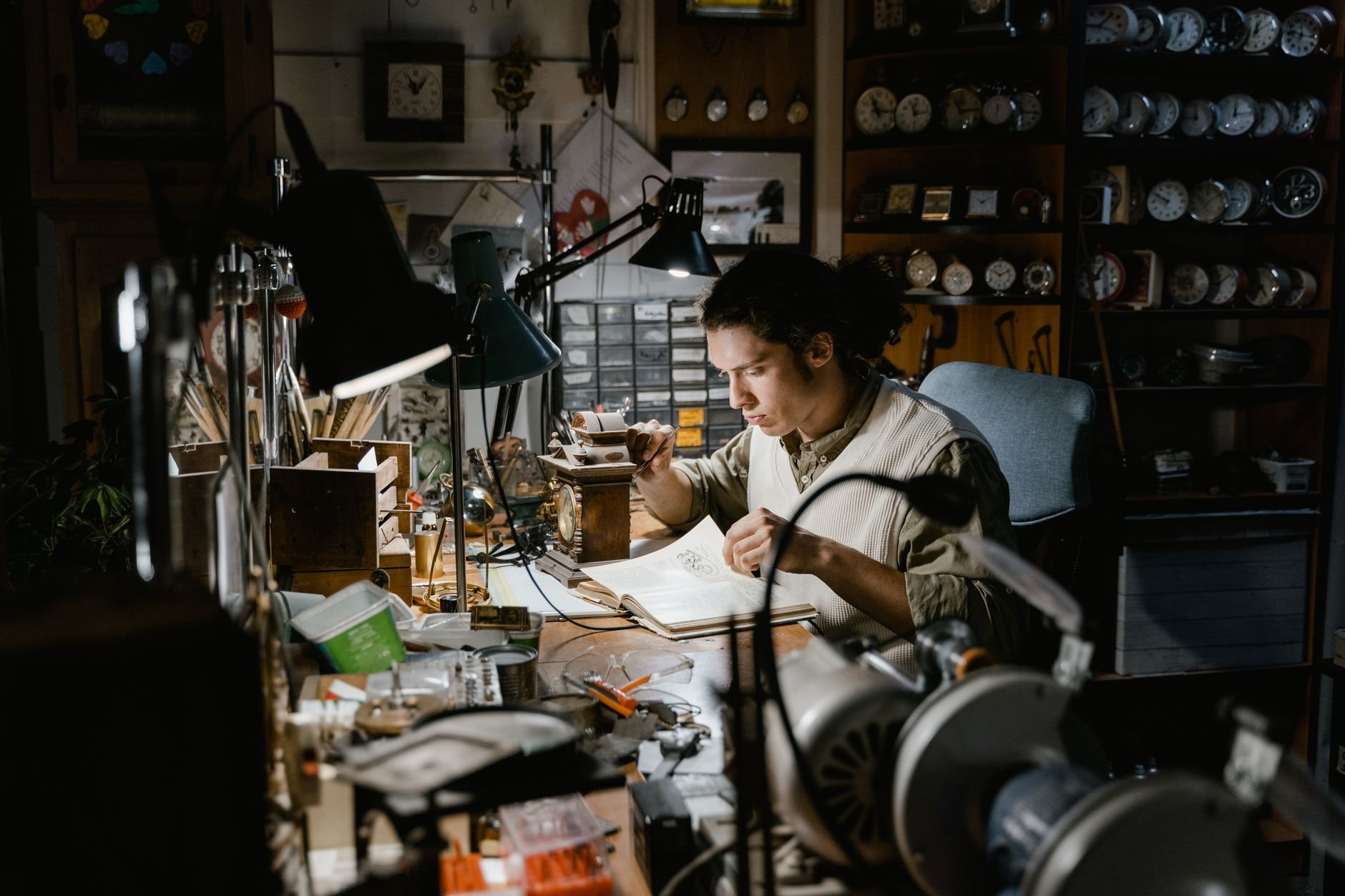 A craftsman working on a timepiece in a clock-filled workshop