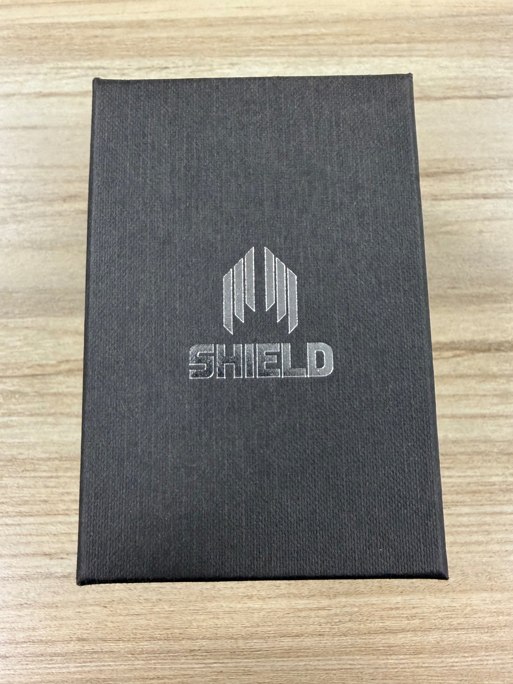 Shield Marco GMT watch box, closed, with silver Shield logo embossed on black textured lid