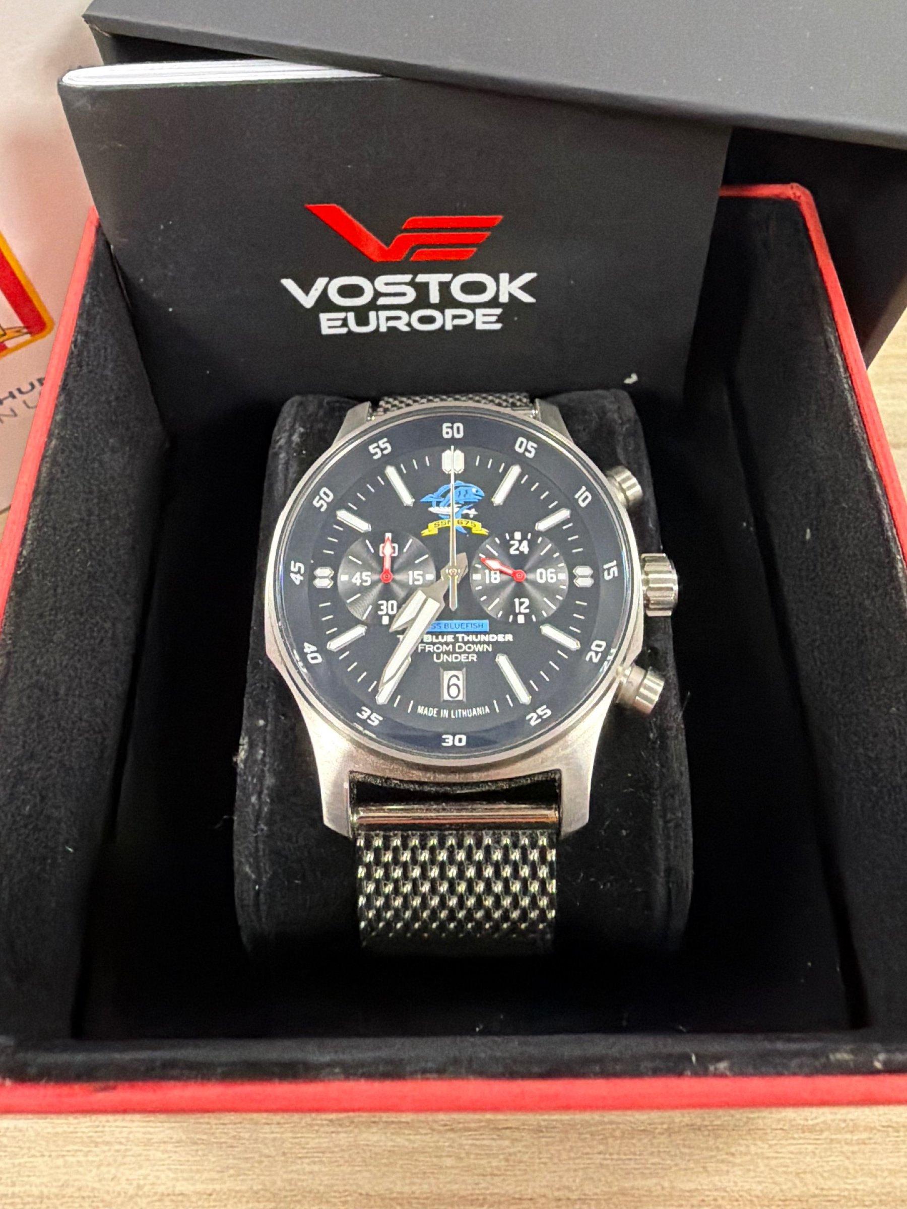 Vostok-Europe USS Bluefish SSN-675 chronograph dial closeup showing USS Bluefish badge, Blue Thunder From Down Under inscription, and stainless mesh bracelet