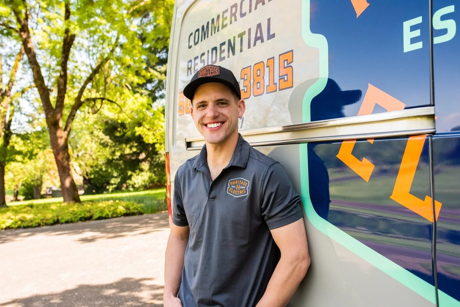 Brandon Taylor, founder of Heritage Electric, smiling next to the Heritage Electric service van