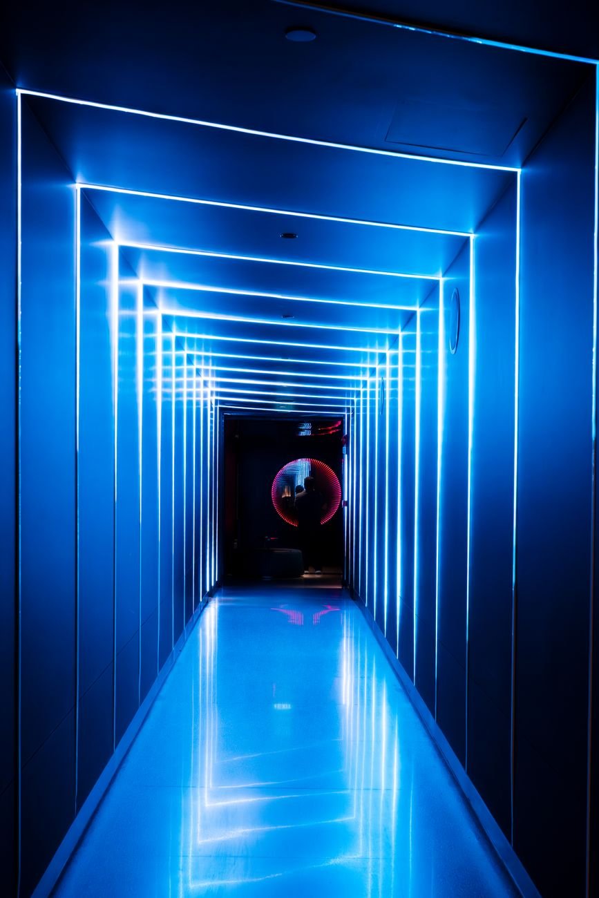 Explore a futuristic corridor with glowing neon lights and geometric shapes, creating a sci-fi atmosphere.