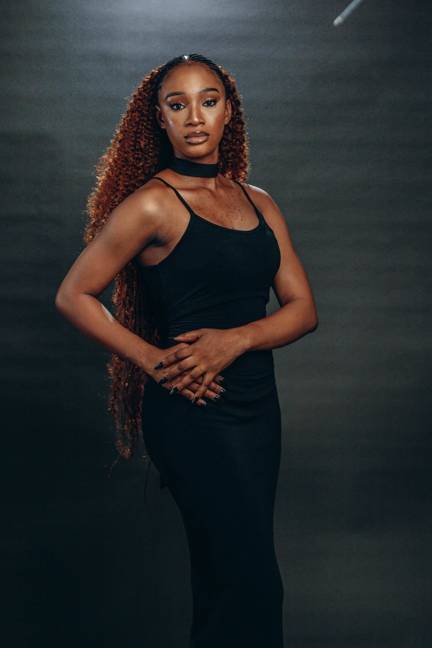 Striking portrait of a woman in a black dress with long curly hair, evoking elegance and grace.