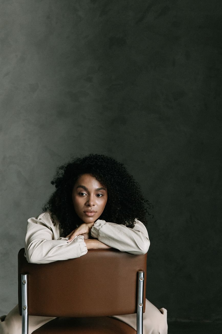 Portrait of a woman with afro hair in a minimalist studio.