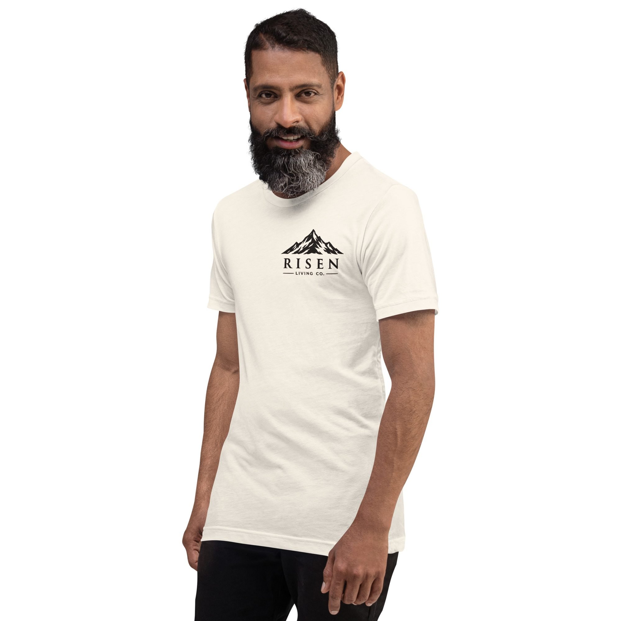 Man wearing Risen Living Co. mountain wordmark tee in vintage white, angled view