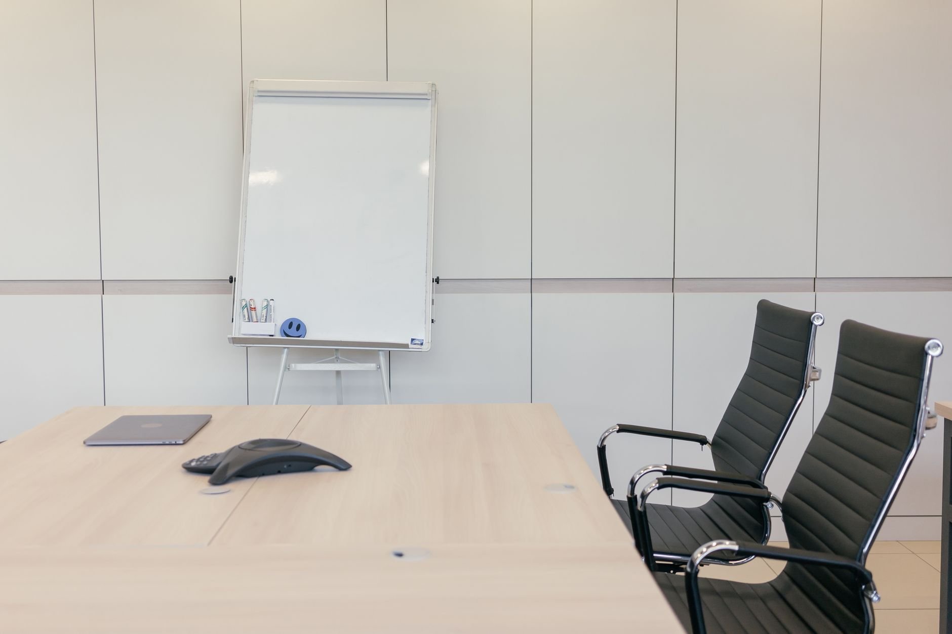 Sleek conference room with chairs, table, and whiteboard ready for a meeting.