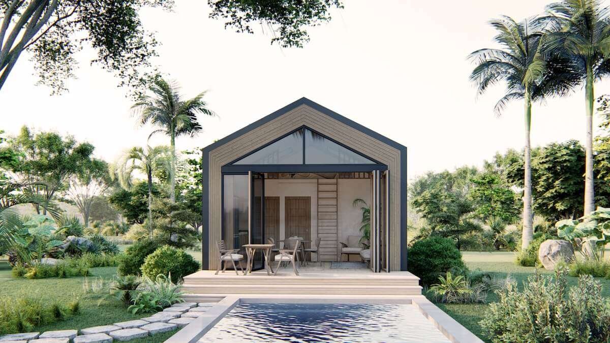Modern custom tiny home with dark steel frame, wood cladding, and bifold glass doors opening to a deck and pool surrounded by tropical palms