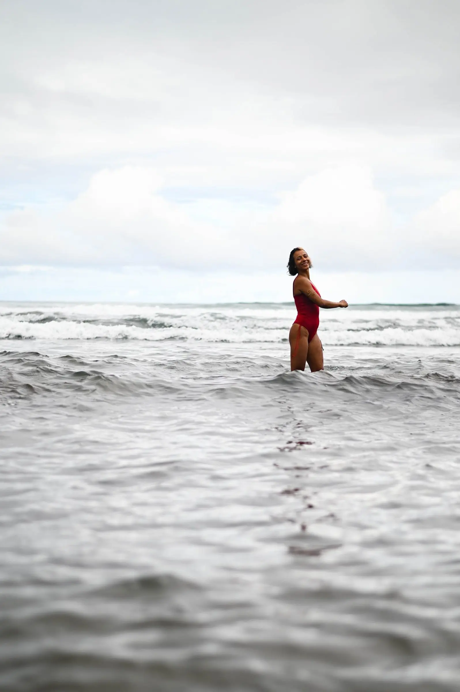 Angie Gómez joyful in ocean waves — the spirit of Neera Yoga