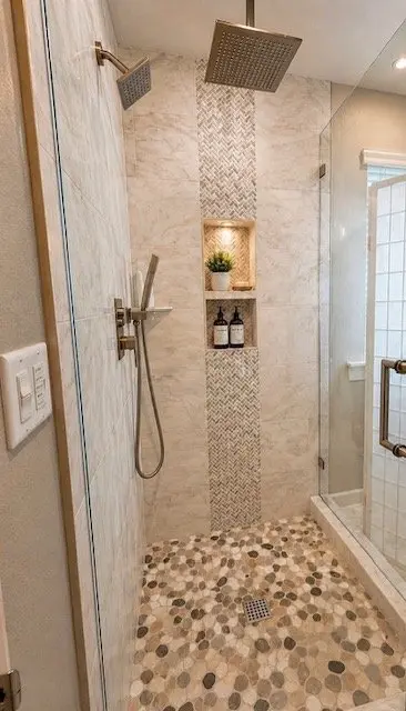 Spa-style shower with marble herringbone tile, pebble floor, and rain head