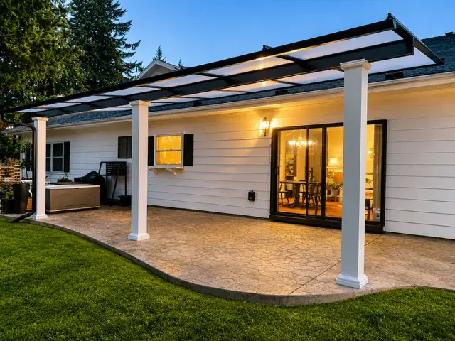 Illuminated covered patio at dusk with stamped concrete and pergola structure